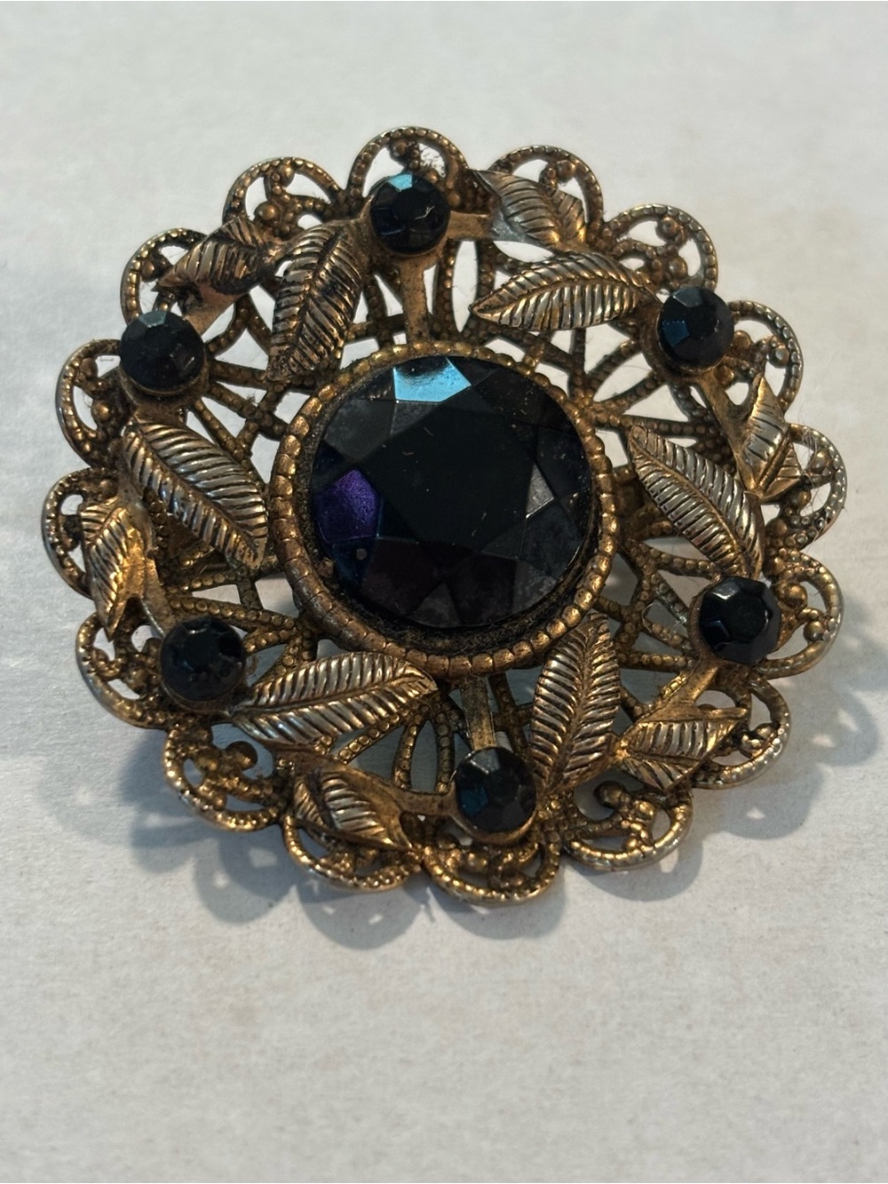 vintage brooch features black faceted rhinestones set gold-tone leaf detailing